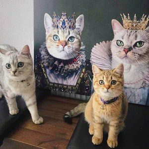 May include: Three cats wearing crowns and regal attire. A white cat with blue eyes is wearing a blue and gold crown and a white and gold ruff. A gray cat with green eyes is wearing a gold crown and a white ruff. A brown tabby cat with green eyes is wearing a purple collar with a bell. The cats are sitting on a wooden surface.