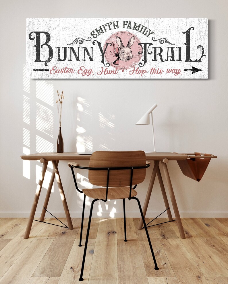 May include: White wooden sign with black text that reads "Smith Family Bunny Trail - Easter Egg Hunt Hop this way" with a pink circle containing a black and white illustration of a bunny rabbit.