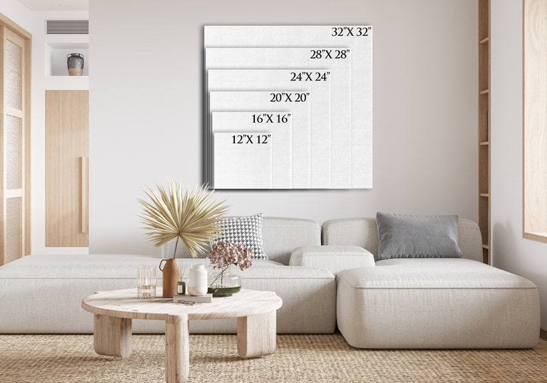 May include: A white canvas with different size options listed in inches. The canvas is hanging on a white wall in a living room setting with a white couch and a wooden coffee table.