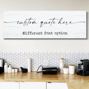 May include: White wooden sign with black text that reads "custom quote here" and "different font option". The sign is hanging on a white wall above a kitchen counter with white hexagonal tiles.