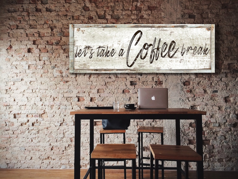 May include: A rustic wooden sign with white paint and black lettering that reads "let's take a coffee break". The sign is hanging on a brick wall above a table with four chairs.