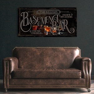 May include: A rustic wooden sign with the text "The William's Basement Bar" in a stylized font. The sign features a depiction of glasses of beer and the text "Cold Beer Open 24 Hours" and "Good Times Good Friends".