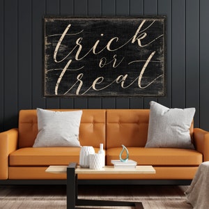 K&ouml;nnte beinhalten: Schwarzes Holzschild mit wei&szlig;er Schrift, die in einer kursiven Schriftart "trick or treat" lautet. Das Schild ist abgenutzt und hat einen rustikalen Look.
