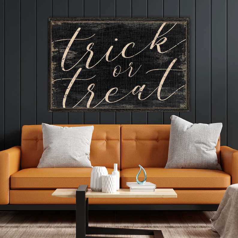 K&ouml;nnte beinhalten: Schwarzes Holzschild mit wei&szlig;er Schrift, die in einer kursiven Schriftart "trick or treat" lautet. Das Schild ist abgenutzt und hat einen rustikalen Look.