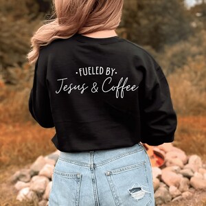 May include: Black sweatshirt with white text that reads "Fueled by. Jesus & Coffee".