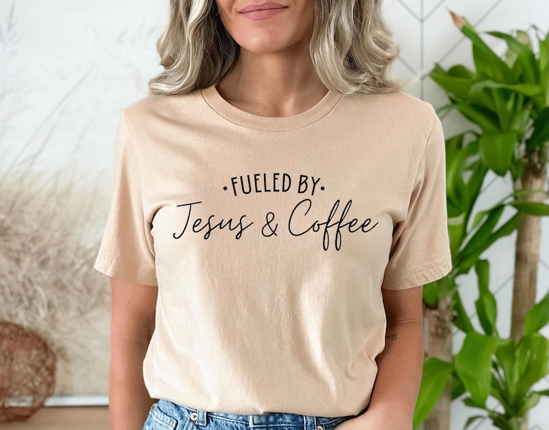 May include: A beige t-shirt with the text "Fueled by: Jesus & Coffee" printed in black.
