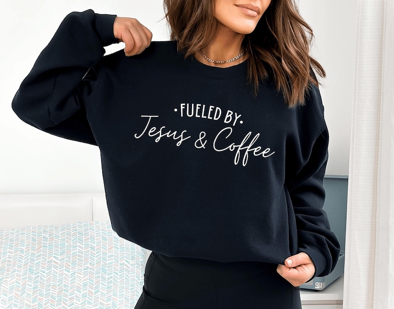 May include: Black sweatshirt with white text that reads "Fueled by: Jesus & Coffee".