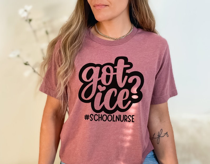 May include: A mauve t-shirt with the text "got ice? #schoolnurse" in black lettering.