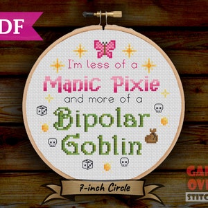 May include: A 7-inch embroidery hoop with a white background and colorful cross-stitch design. The design features a pink butterfly, yellow stars, and the text "I'm less of a Manic Pixie and more of a Bipolar Goblin".