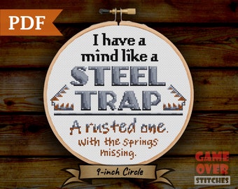 May include: A cross-stitch pattern for a 9-inch embroidery hoop featuring the text "I have a mind like a STEEL TRAP. A rusted one. With the springs missing." The pattern is in black and white with a gray background.
