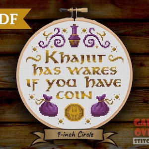 May include: A 9-inch round embroidery hoop with white fabric depicting a cross-stitch design. The design features gold text that reads "Khajiit has wares if you have coin" with purple and gold accents. The design also includes two purple bags and a gold coin.