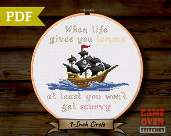 May include: A cross-stitch pattern featuring a pirate ship sailing on the sea with the text "When life gives you lemons at least you won't get scurvy". The pattern is designed for a 9-inch embroidery hoop.