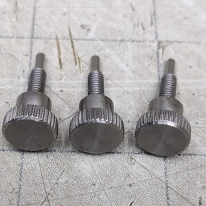 May include: Three silver thumbscrews with a knurled head and a threaded shaft.