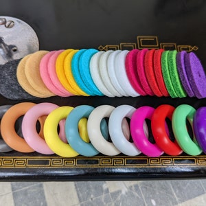 Op de afbeelding: Een set kleurrijke viltcirkel en ringen. De cirkels zijn gestapeld in een regenboogpatroon, terwijl de ringen in een rij zijn gerangschikt. De ringen zijn gemaakt van verschillende materialen, waaronder hout en plastic.
