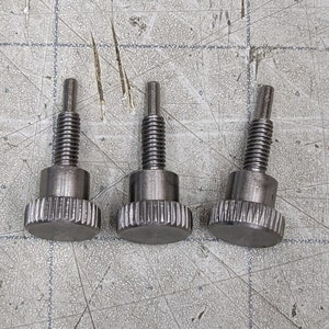 May include: Three silver thumbscrews with a knurled head and a threaded shaft.