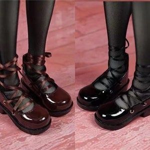 May include: Two pairs of black patent leather shoes with brown ribbon laces. The shoes have a low heel and a rounded toe.