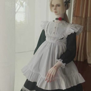 May include: A white and black maid dress with a ruffled collar and apron. The dress has a black bow on the shoulder and a red flower on the collar.