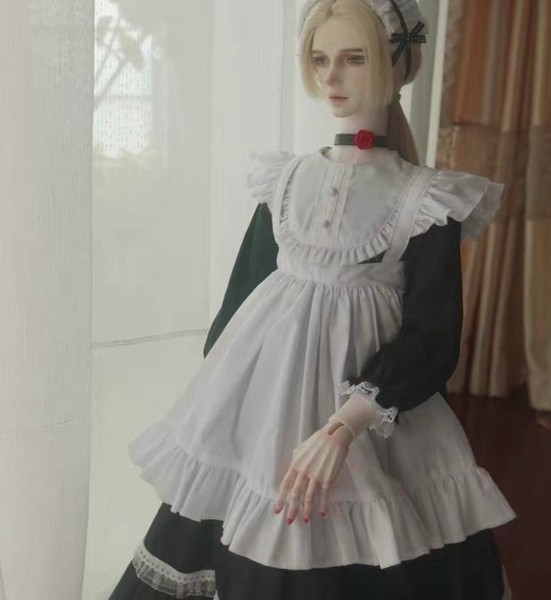 May include: A white and black maid dress with a ruffled collar and apron. The dress has a black bow on the shoulder and a red flower on the collar.