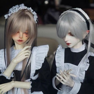 May include: Two dolls wearing black and white maid outfits. One doll has long, light brown hair with a white lace headband and black ribbons. The other doll has short, silver hair with a white lace headband and black ribbon.
