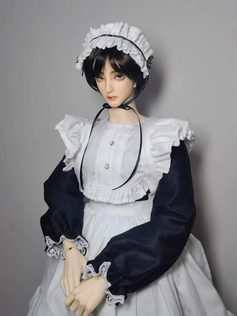 May include: A doll wearing a white and black maid outfit with a white lace collar and cuffs. The doll has black hair and is wearing a white lace headband.