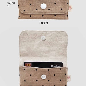 May include: A beige fabric wallet with black polka dots, measuring 11cm x 7cm when closed. The interior is a lighter beige. The wallet has a white snap closure and fits 10-13 cards. A CIBC Dividend card is visible inside.