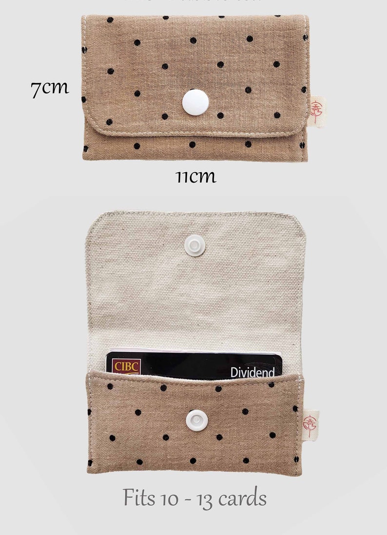 May include: A beige fabric wallet with black polka dots, measuring 11cm x 7cm when closed. The interior is a lighter beige. The wallet has a white snap closure and fits 10-13 cards. A CIBC Dividend card is visible inside.