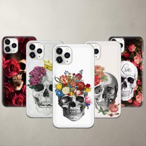 May include: Five smartphone cases featuring skull and floral designs. One case shows a skull with red roses, another a skull with a gold crown and purple roses, a third with a colorful floral crown, a fourth with pink roses, and one with red roses and the word Love.