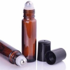 May include: Two amber glass roller bottles with silver roller balls and black caps. One bottle is lying down and the other is standing upright. The caps are off of both bottles.