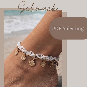 Pode incluir: Tornozeleira de macramé branca com berloques dourados de conchas e circulares. A tornozeleira é usada em um pé coberto de areia, com o oceano ao fundo. O texto na imagem diz "Makramee Schmuck" e "PDF Anleitung".
