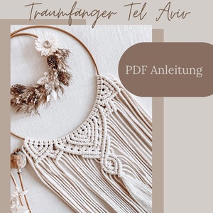 Puede incluir: Un atrapasueños de macramé blanco con un aro dorado y un borlón. El atrapasueños está colgado de una pared blanca y tiene un arreglo de flores secas en el aro. El texto "PDF Anleitung" es visible en la imagen.