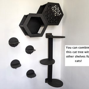 May include: Black cat tree with multiple shelves and a hexagonal cat condo. The cat tree is mounted on a wall and has a post with a scratching surface. The text "You can combine this cat tree with other shelves for cats!" is visible in the image.