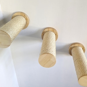 May include: Three natural wood cat scratching posts with sisal rope covering. The posts are mounted to a white ceiling.