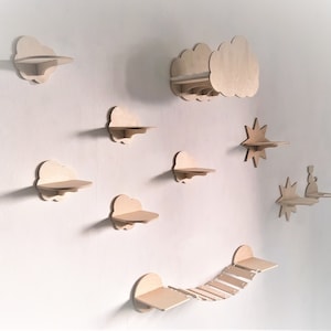 Könnte beinhalten: Ein Set aus neun Wandregalen aus Holz in Form von Wolken, Sternen und einer Brücke. Die Regale sind alle aus Naturholz gefertigt und haben ein schlichtes, minimalistisches Design.