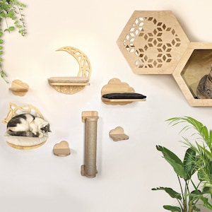Könnte beinhalten: Ein Satz aus Holzkatzenregalen in Form eines Halbmondes, Wolken und Sechsecken. Die Regale sind an einer weißen Wand montiert. Eine Katze schläft auf einem der Regale.