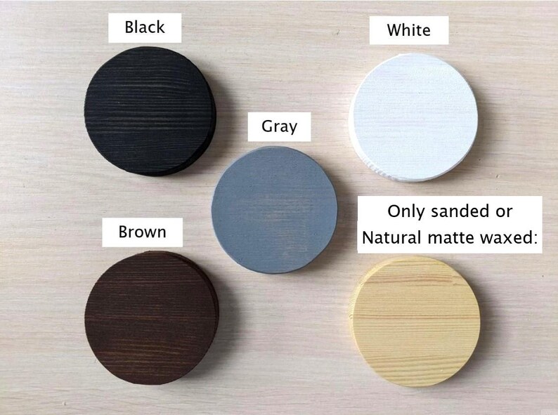 Op de afbeelding: Vijf houten cirkels in verschillende kleuren: zwart, wit, grijs, bruin en naturel hout. De tekst "Only sanded or Natural matte waxed" staat onder de cirkels.