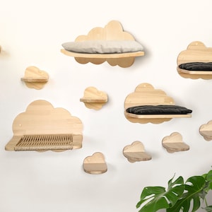 Könnte beinhalten: Ein Set aus zehn hölzernen Katzenregalen in Wolkenform, die an einer weißen Wand montiert sind. Einige Regale haben Kissen, während andere mit Sisalseil bedeckt sind.