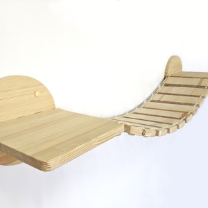 May include: A wooden cat bridge with a curved design and a platform. The bridge is made of natural wood and has a rope-like texture. The platform is attached to the wall with two screws.