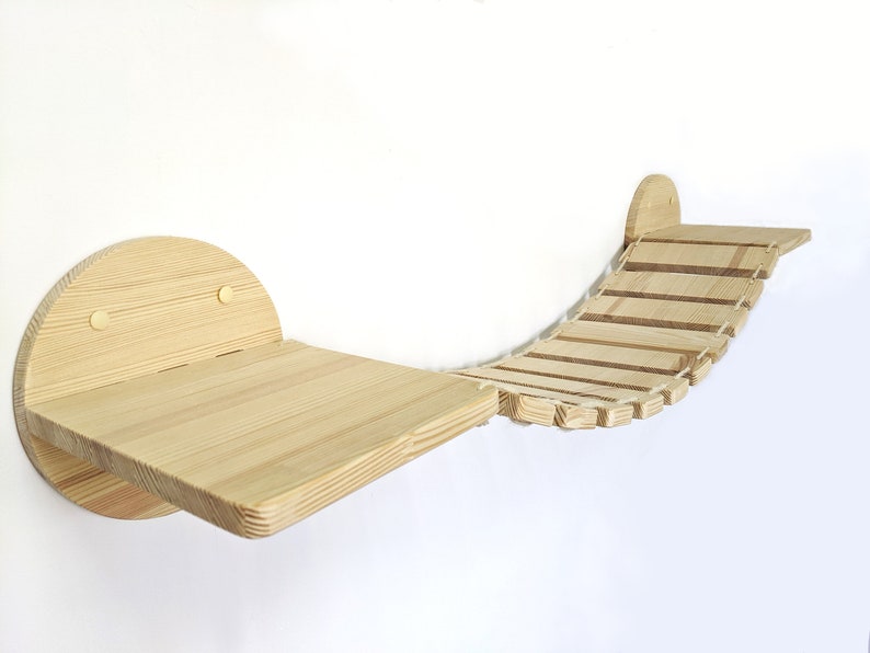 May include: A wooden cat bridge with a curved design and a platform. The bridge is made of natural wood and has a rope-like texture. The platform is attached to the wall with two screws.