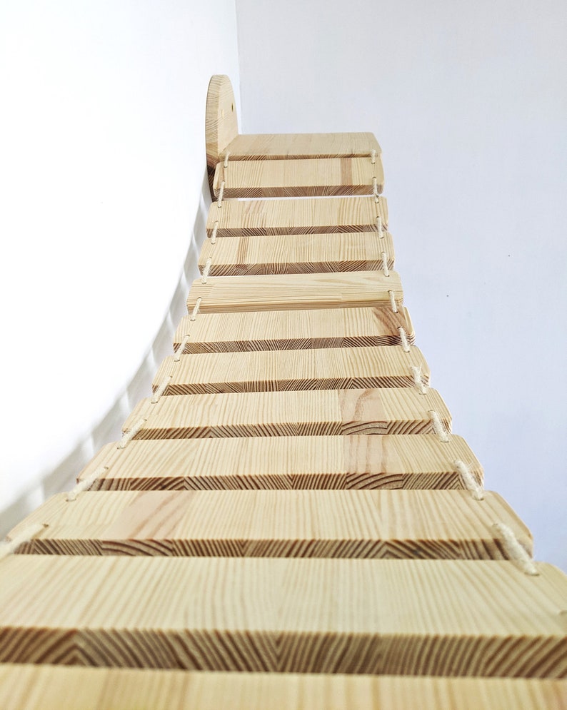 May include: A wooden cat climbing bridge with a curved design and rope accents. The bridge has multiple steps for cats to climb on.