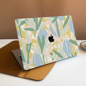 Puede incluir: Un ordenador portátil con una piel de diseño floral. El diseño presenta formas abstractas en tonos de azul, verde, amarillo y rosa.