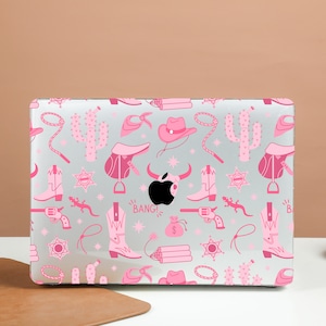 May include: Pink and white laptop skin with a western theme. The design features cowboy boots, hats, cacti, and other western icons. The skin has a glossy finish and is easy to apply.