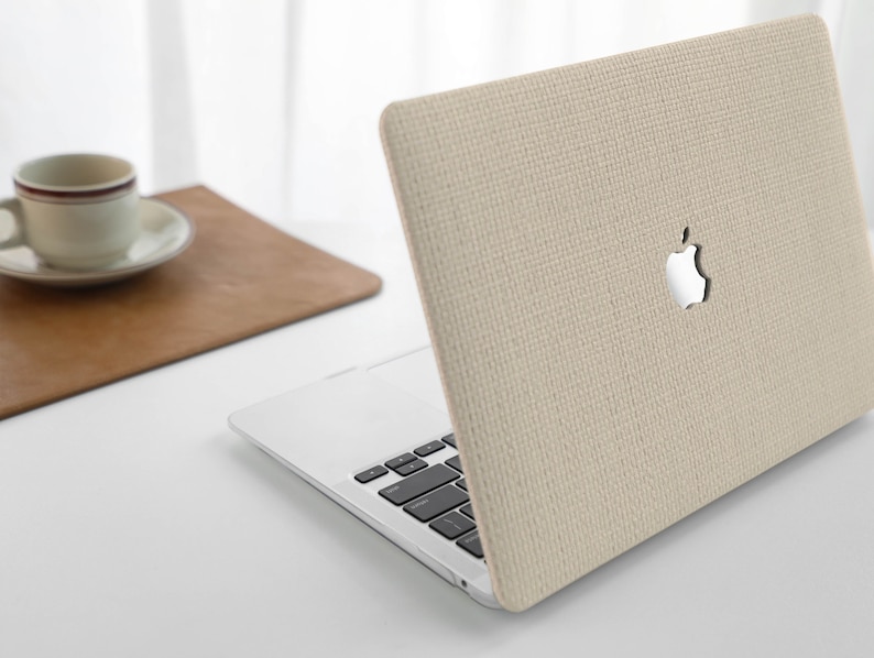 Puede incluir: Una funda para port&aacute;til beige con un acabado de tejido texturizado. La funda tiene un recorte para el logotipo de Apple.