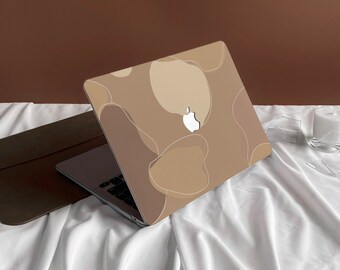 May include: A laptop computer with a brown and beige abstract design on the lid. The laptop is closed and sitting on a white surface.