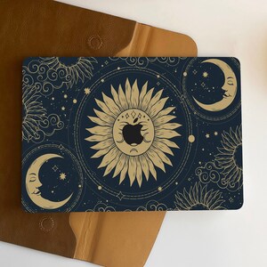 May include: A dark blue laptop skin with a gold celestial design featuring moons, stars, and suns. The design has a vintage, mystical feel.
