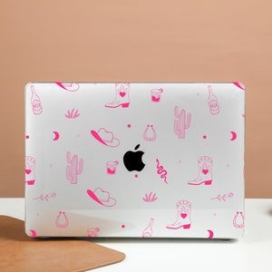 May include: White laptop with a pink and white design featuring cowboy boots, cacti, horseshoes, and beer bottles. The design is repeated across the entire laptop cover.