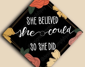 Può includere: Un quadrato nero con la scritta bianca "SHE BELIEVED she could SO SHE DID". Il design include un bordo dorato ed elementi floreali arancioni, gialli e verdi. Citazione motivazionale.