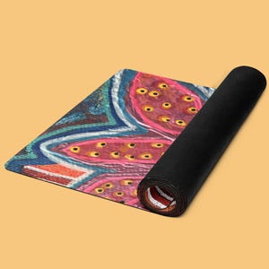 May include: A rectangular yoga mat partially rolled up, featuring a vibrant abstract design with pink, blue, and orange sections. The surface displays a pattern of pink organic shapes filled with small yellow dots, outlined by blue and white lines.