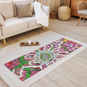 May include: A rectangular yoga mat featuring a vibrant, abstract floral design with a central green textured circle surrounded by radiating white petals, set against a deep magenta and bright green background with scattered circular accents.