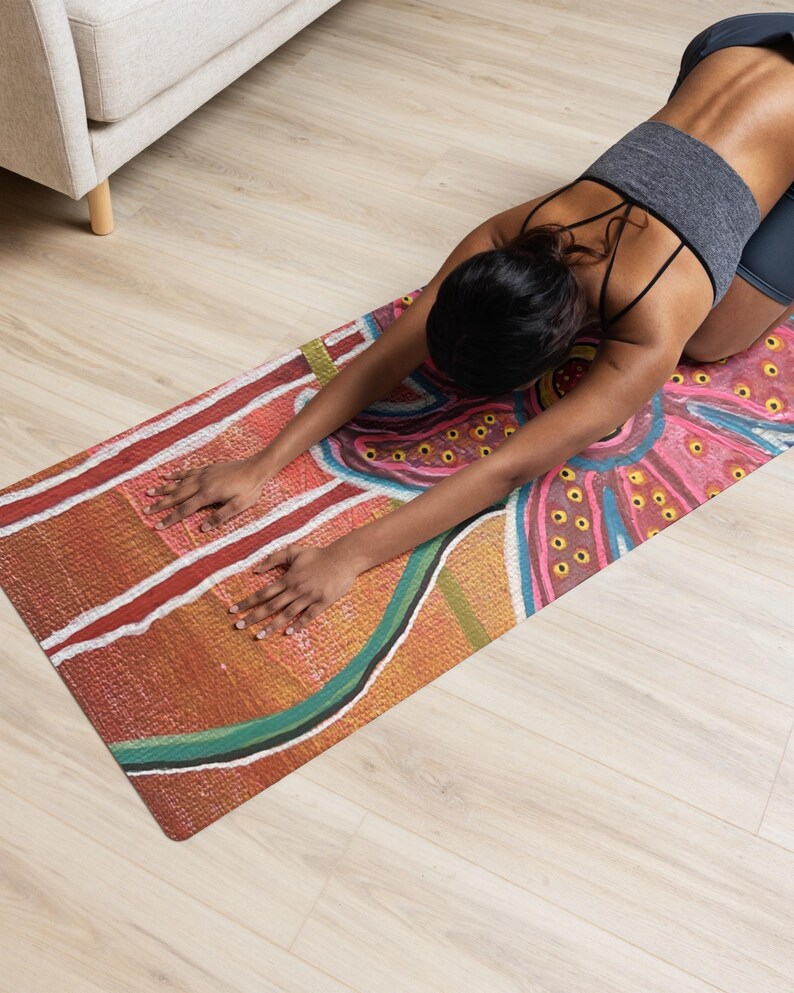 May include: A rectangular yoga mat featuring a vibrant, abstract design with earthy tones of orange, red, and yellow, accented by swirling blue lines and dotted patterns. The surface has a textured appearance, showcasing a colorful, artistic print.