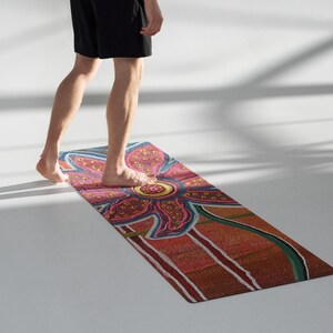 May include: A rectangular yoga mat featuring a vibrant, multi-colored floral pattern with a large pink and yellow central flower. The design includes textured orange, red, and green sections with white line accents, creating a detailed, artistic surface.